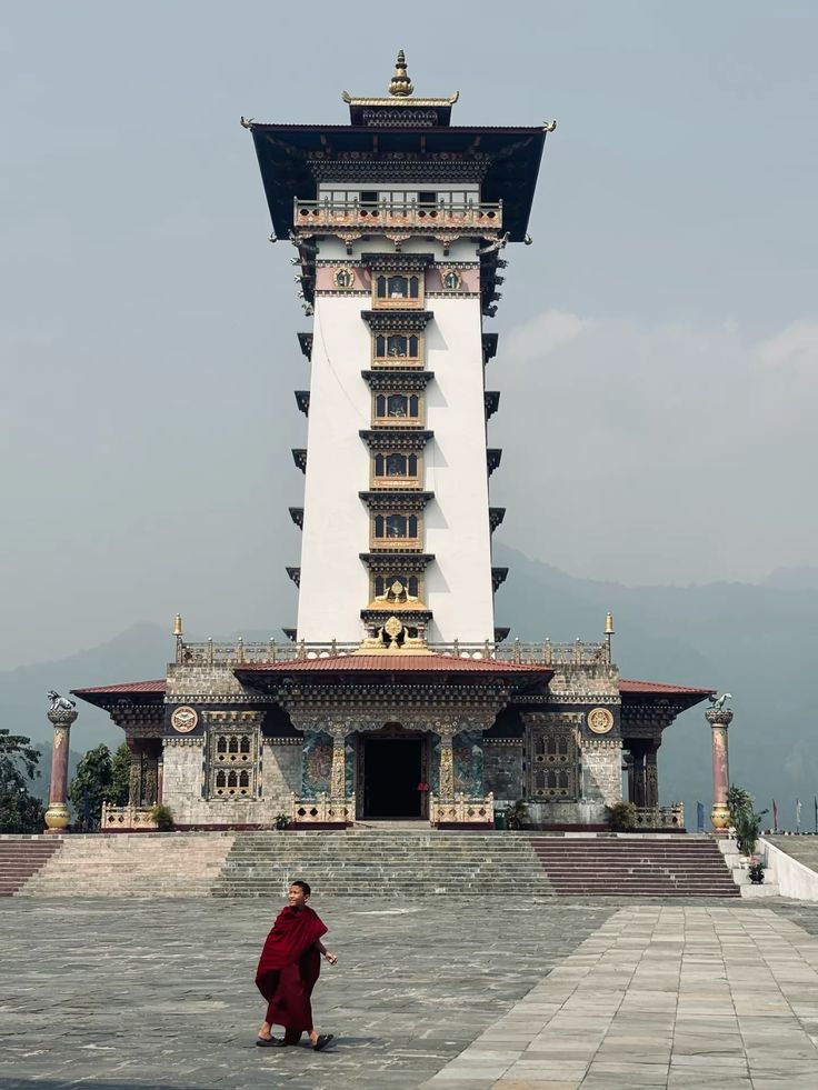 Tall temple tower in Chhukha with a monk walking past