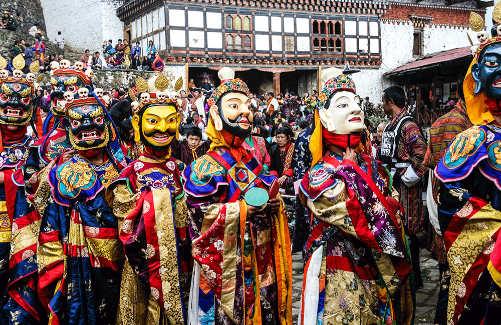 Masked dancers in ornate costume at Jambay Lhakhang Drup