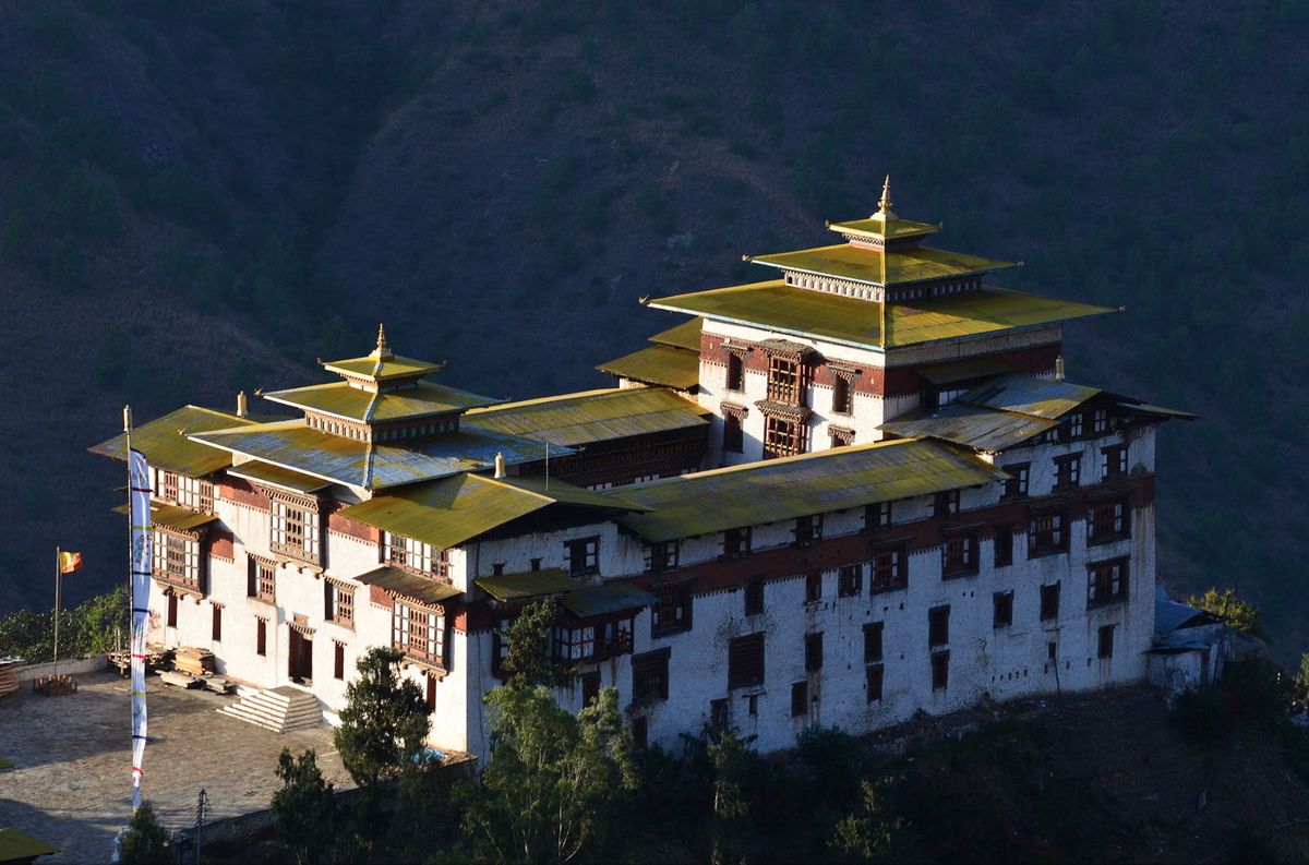 Trashigang Dzong lit by evening light above the hills