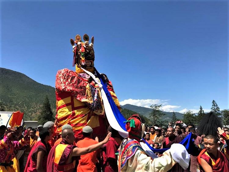 Elaborate costumed figure carried through the crowd at Wangdue Tshechu